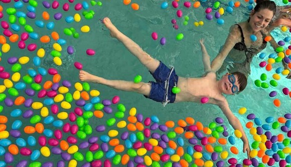 A child floats in a swimming pool filled with floating Easter Eggs