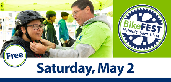 A BikeFest volunteer helps a young cyclist secure her helmet.