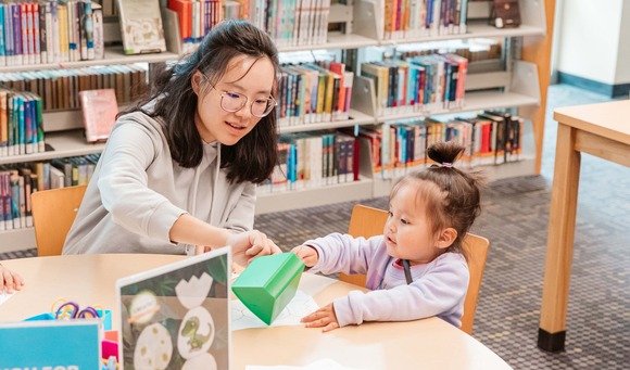 Library staff worker playing with a toddler at a table