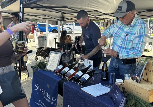 Wine vendors pour wine at a booth