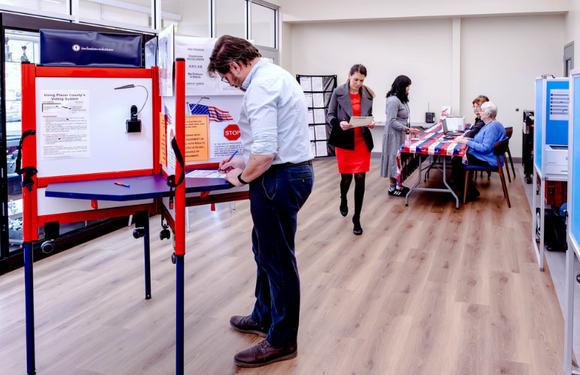 A man drops a ballot into a ballot box at a Voting Center.