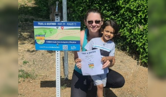 A mom hugs her son next to a Trail-A-Bration sign