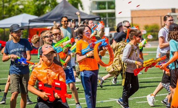 A group of children play while holding toy blasters