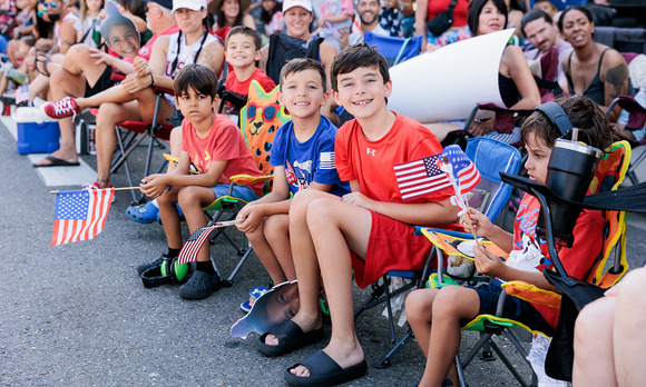 A group of three young boys smile at the camera as they wait for the 4th of July festival to begin