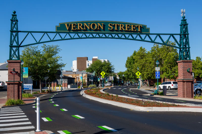 An arch displays "Vernon Street" as it spans a tree-line roadway with pedestrian crossings and bike lanes.