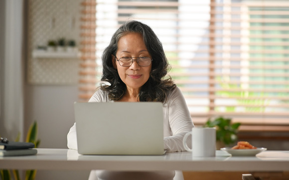 A woman smiles as she uses a laptop