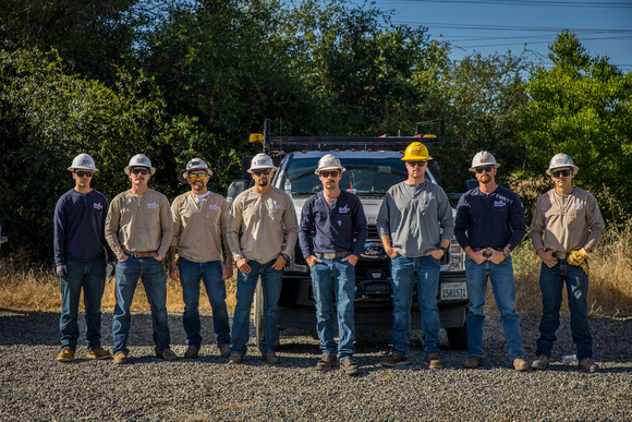 Electric field worker team stand in front of an Electric Utility Truck