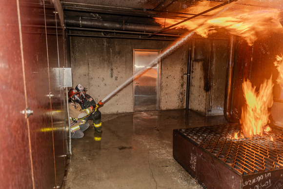 Photo of two people in the Fire Cadet Program spraying down a fire