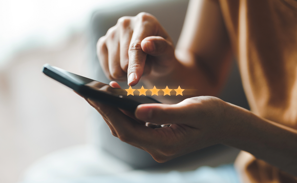 A person holds a phone in one hand as they scroll with their other finger. A graphic of five stars float above the phone.