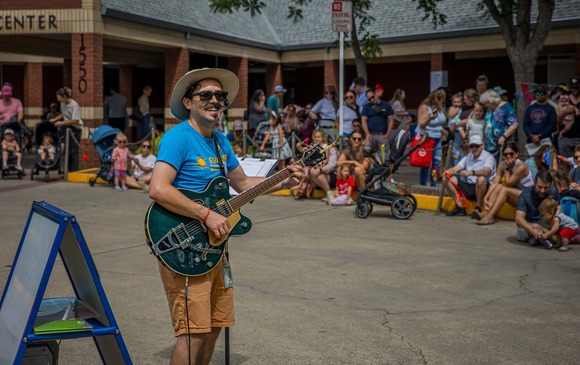 Librarian Joe Lopez plays the guitar and sings to the audience sitting outside Maidu Library