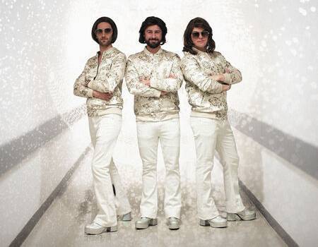Bee Gees tribute band smiles and poses with their arms crossed