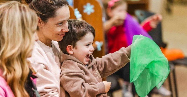 A woman smiles while holding a smiling young boy in her lap for Library Discovery Day