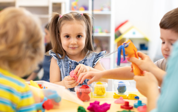 A group of toddlers play with crafts at a table