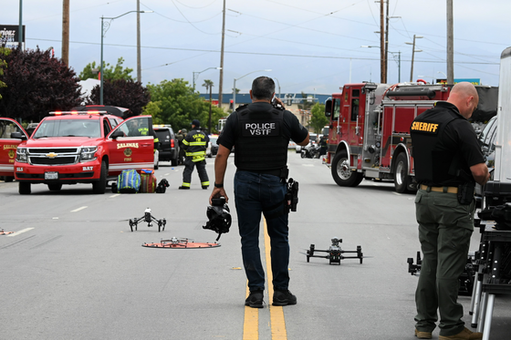 salinas police officer standing on Market Street talking on the phone with fire vehicles and personnel and sheriff's deputy around him