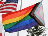progress pride flag on display on the City Hall flag poles