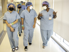 A group of youth dressed in scrubs walk through a hallway with a doctor at ARMC.