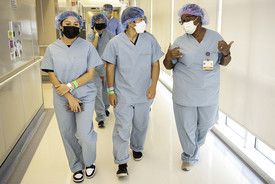 A group of youth dressed in scrubs walk through a hallway with a doctor at ARMC.