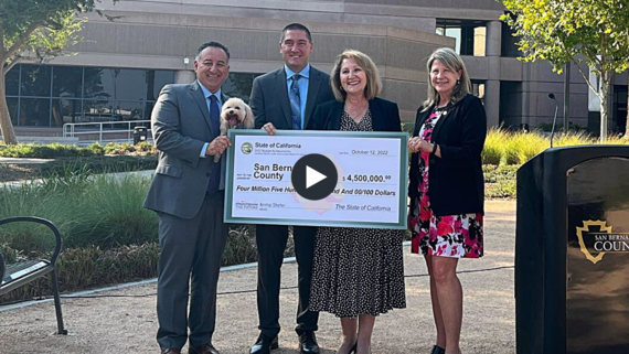 A photo of a large check with four people and a dog for the donation to the animal care facility.