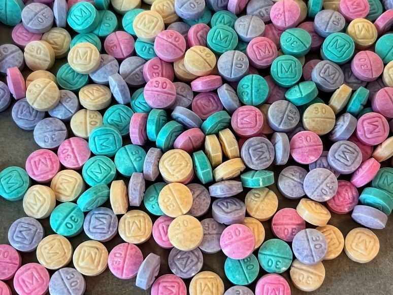 A bunch of rainbow colored pills are shown in a pile.
