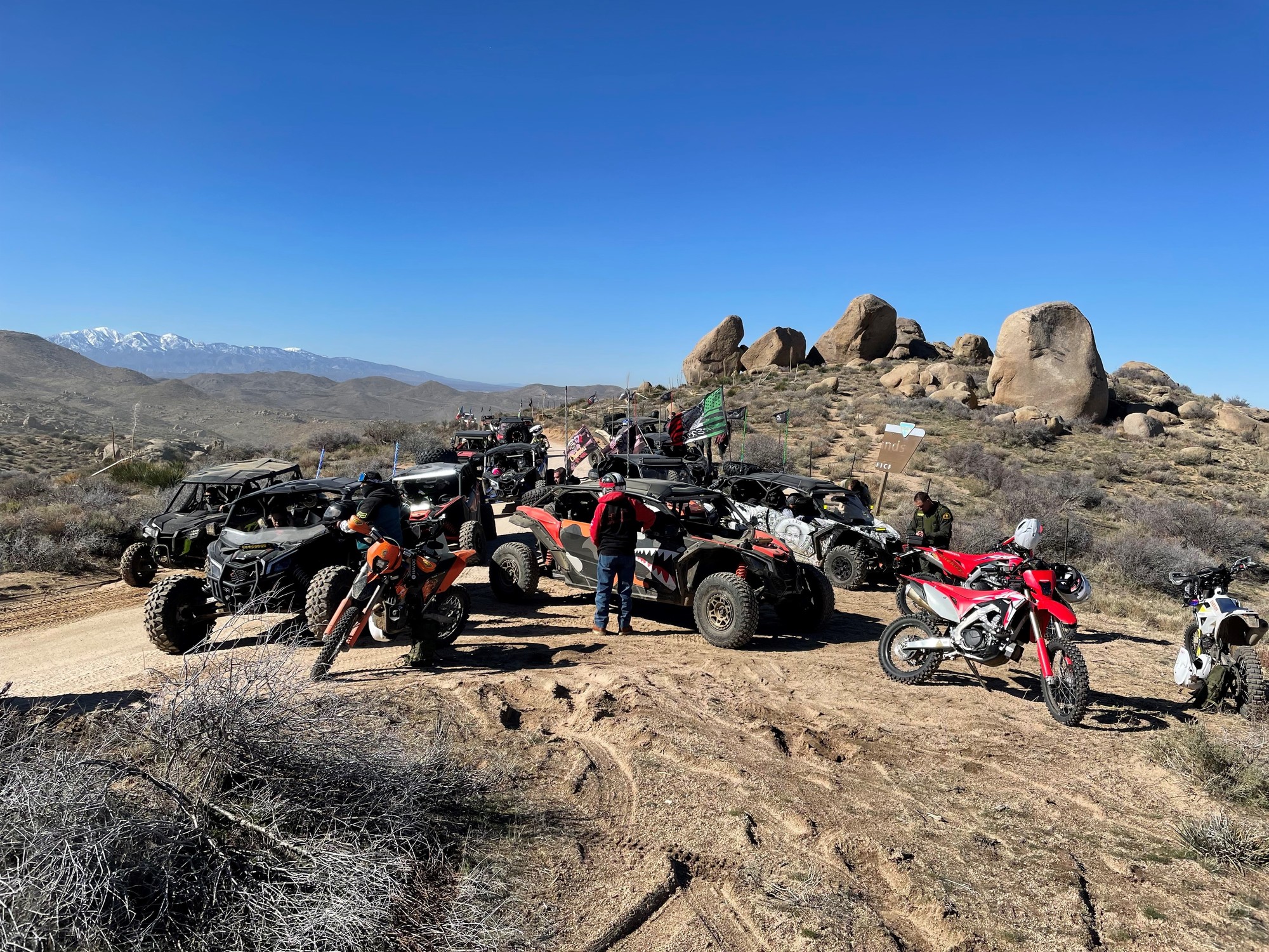 A group of  arked off-road vehicles are seen together in the desert.