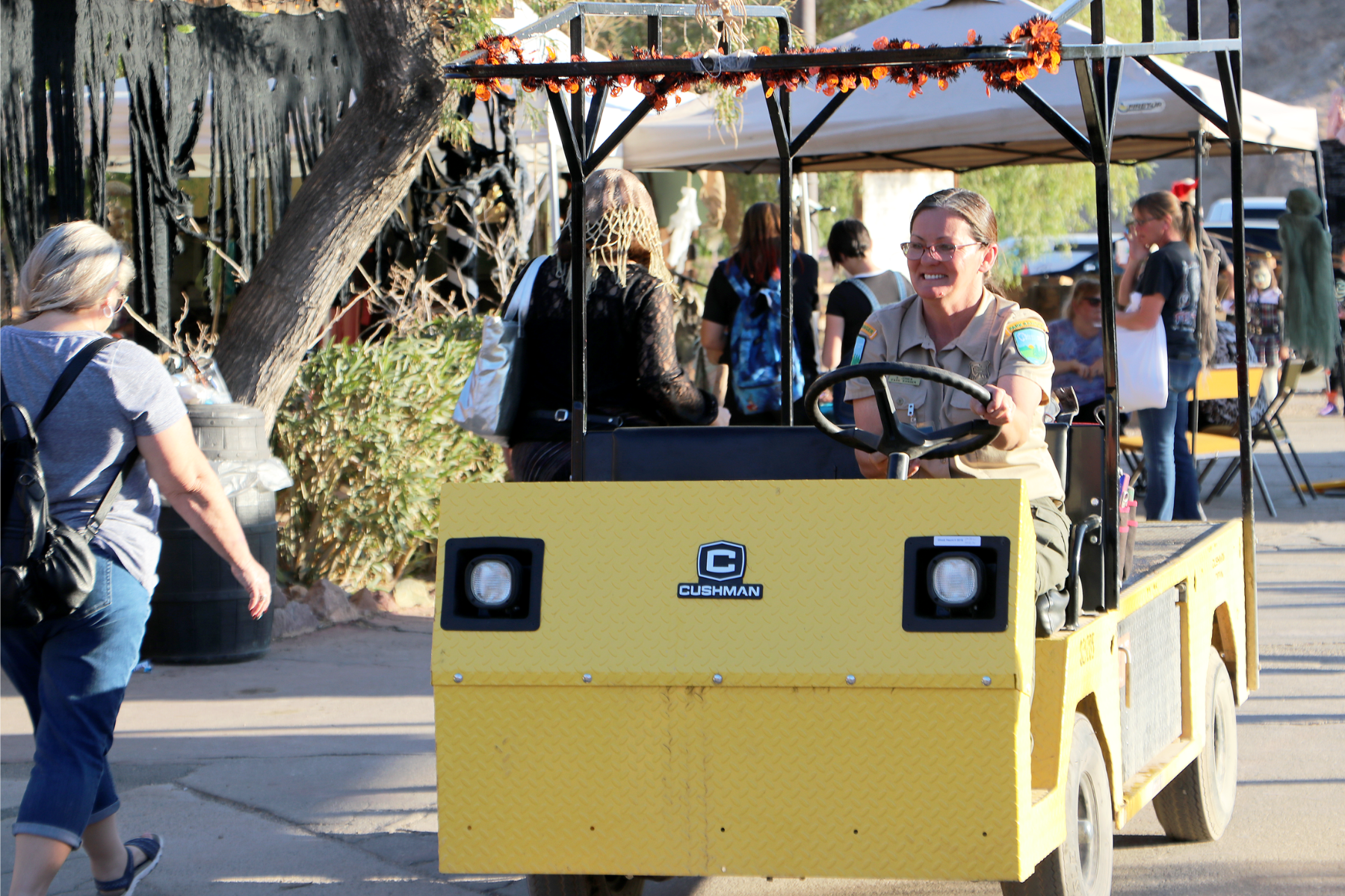 A female park superintendent drives a cart through a crowd of people at Calico Ghost Town.