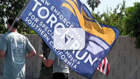 A photo of a man holding a banner with the words law enforcement torch run while running away with a woman next to him outside running.