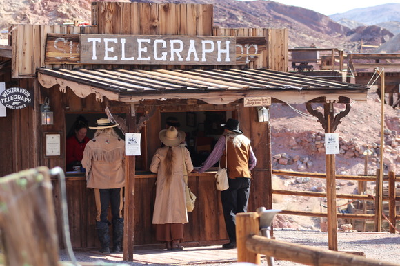 Three people standing at an old time telegraph office at Calico Ghost Town