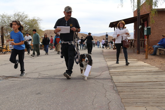 A man and woman with sheltie dog runs through main street at Calico Ghost Town.
