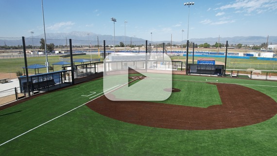 An aerial view of a newly constructed baseball field featuring synthetic turf, backstops and protective netting. 