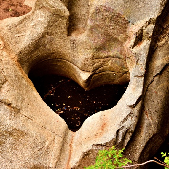 A heart-shaped hollow in a large rock that is partially filled with water.