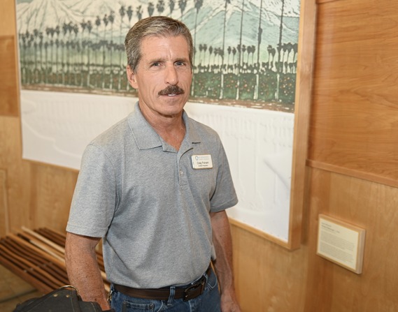 Craig Putnam standing in front of a mural depicting a palm tree-lined landscape.