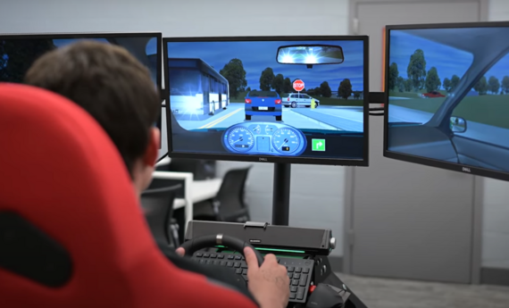 Young driver sits in a driving simulator, staring at a nighttime street scene.
