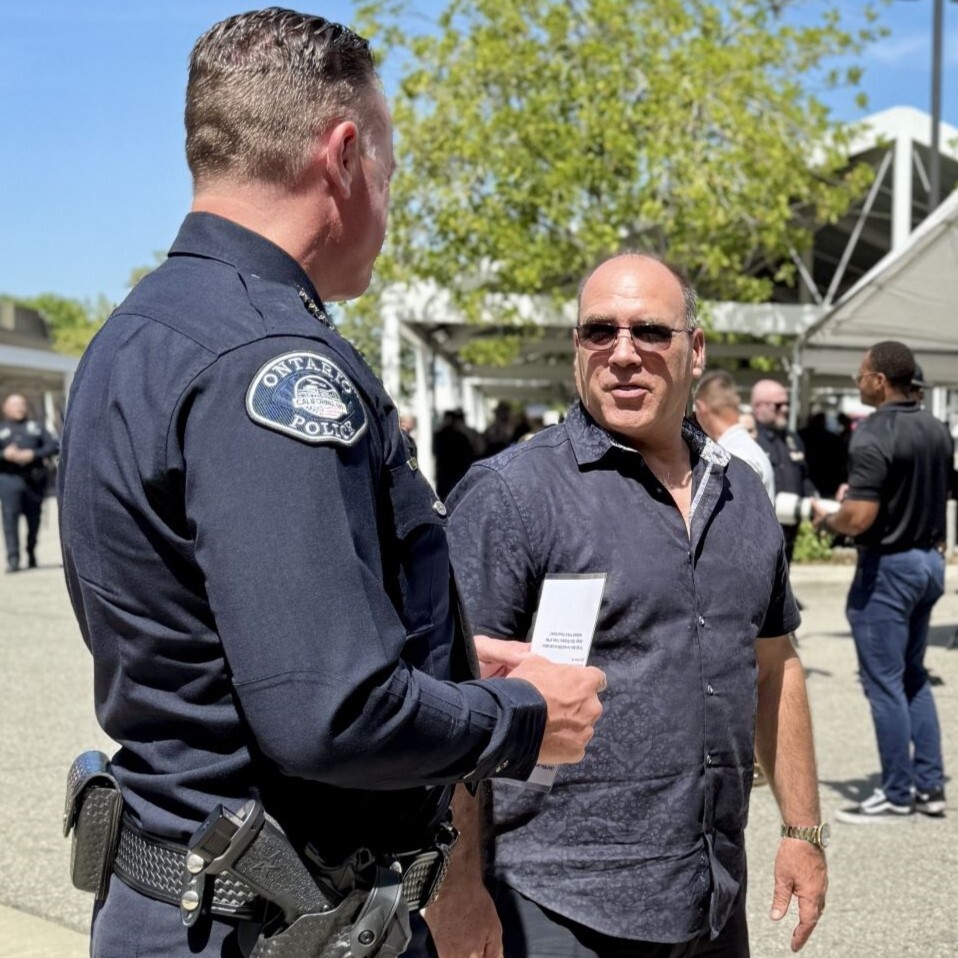 An Ontario police officer speaks with Supervisor Curt Hagman during an outdoor community event.