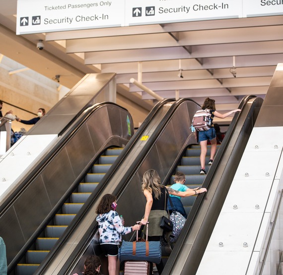 Three women going up the escalator at Ontario International Airport.