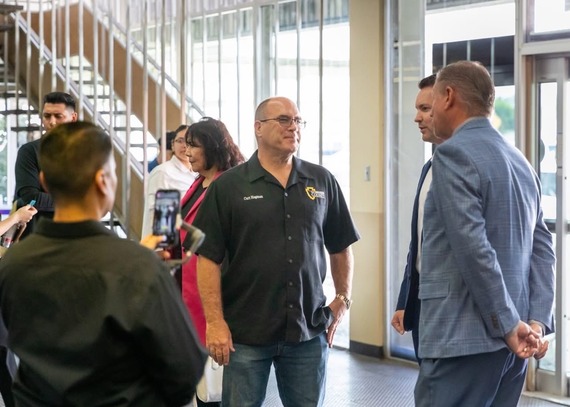 Supervisor Curt Hagman speaks with two males dressed in business attire during a job fair event at Ontario International Airport.