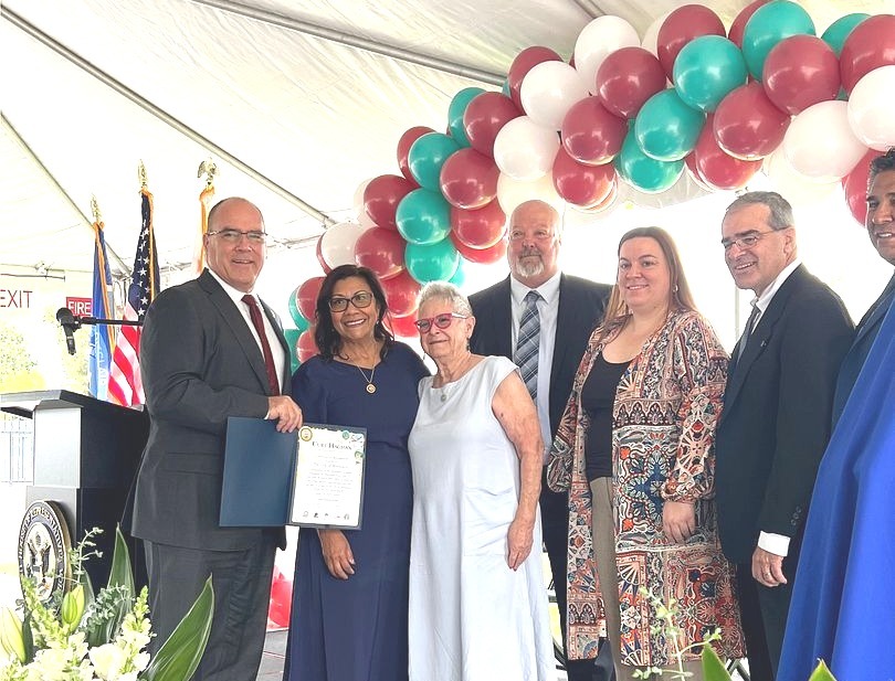 Officials and family pose with certificate at the Paul Eaton Post Office Building Dedication.
