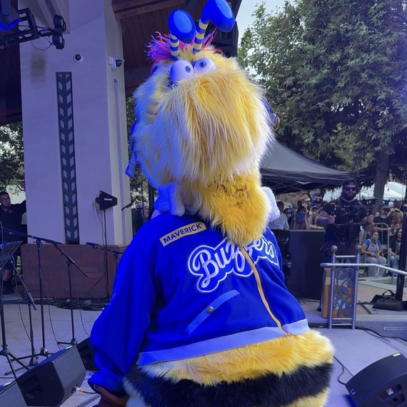 Ontario Tower Buzzers Mascot, Maverick in blue jacket performing on stage at an outdoor event.