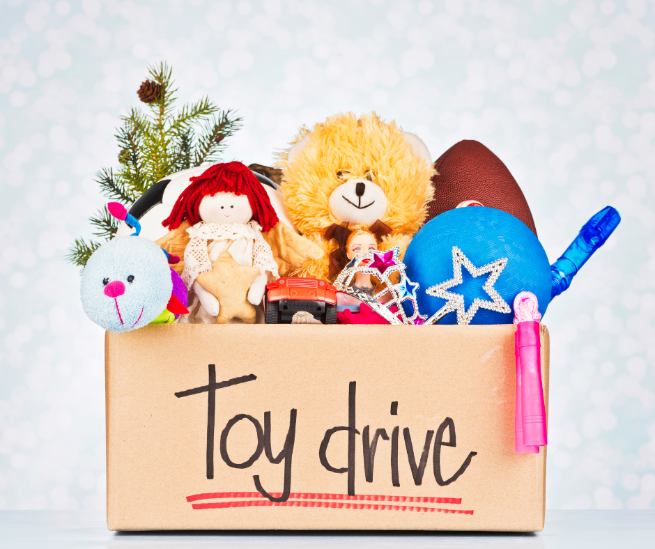 A cardboard box marked TOY DRIVE is filled with a range of items including stuffed animals, cars, and sports equipment.