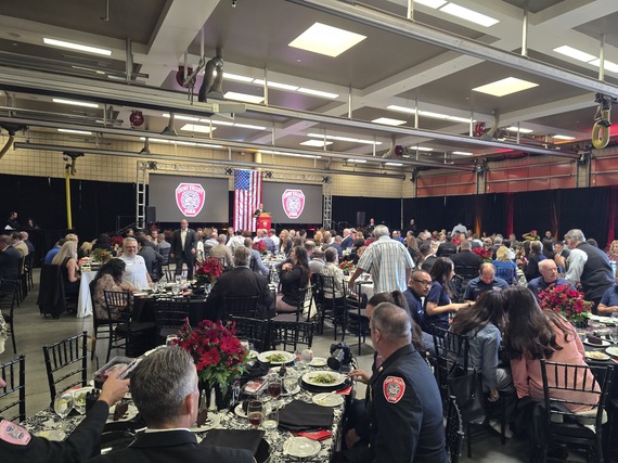 A large audience seated at decorated tables during a Chino Valley Fire banquet with a speaker on stage.