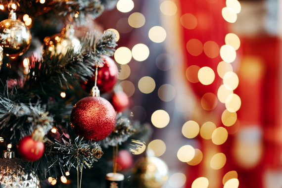 A close-up of a decorated Christmas tree with red ornaments and warm holiday lights. 