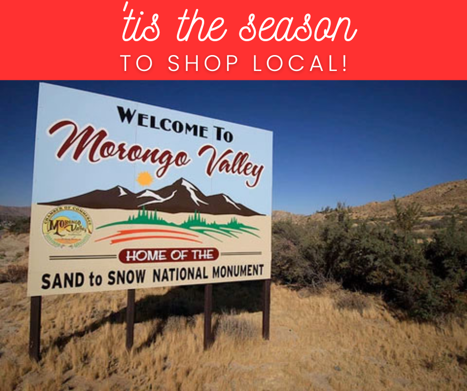 the “Welcome to Morongo Valley” sign, which sits in a desert landscape with dry grass, shrubs, and surrounding hills under a clear blue sky