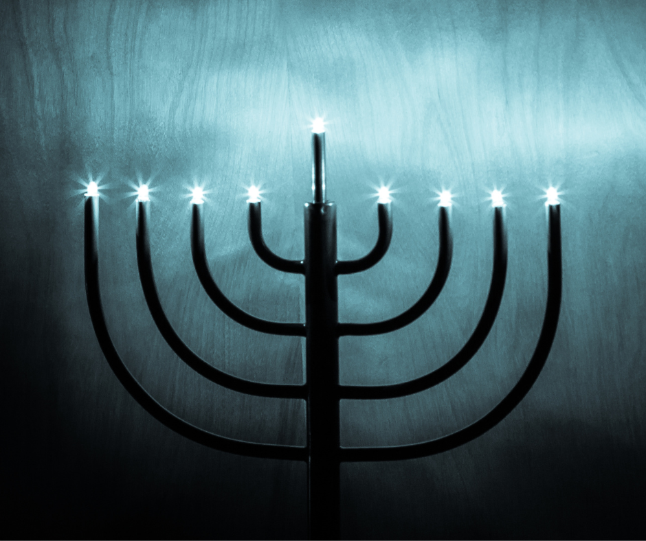 A fully lit menorah stands against a dark blue background
