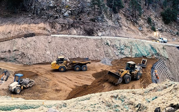 Heavy equipment works to make repairs on the damaged portion of State Route 38 near Angelus Oaks