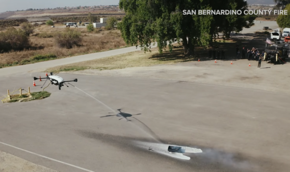 A San Bernardino County Fire Department drone sprays fire retardant on an open flames