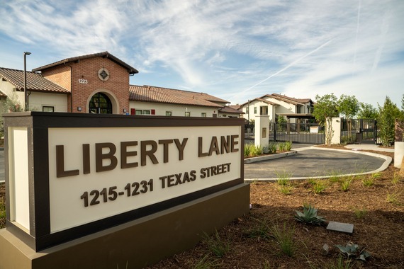 Entrance of Liberty Lane featuring a prominent sign in the foreground and a gated residential community in the background.  