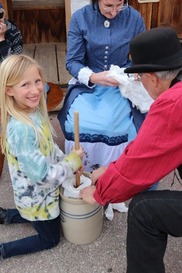 A little girl churns butter at a Calico California Days event.