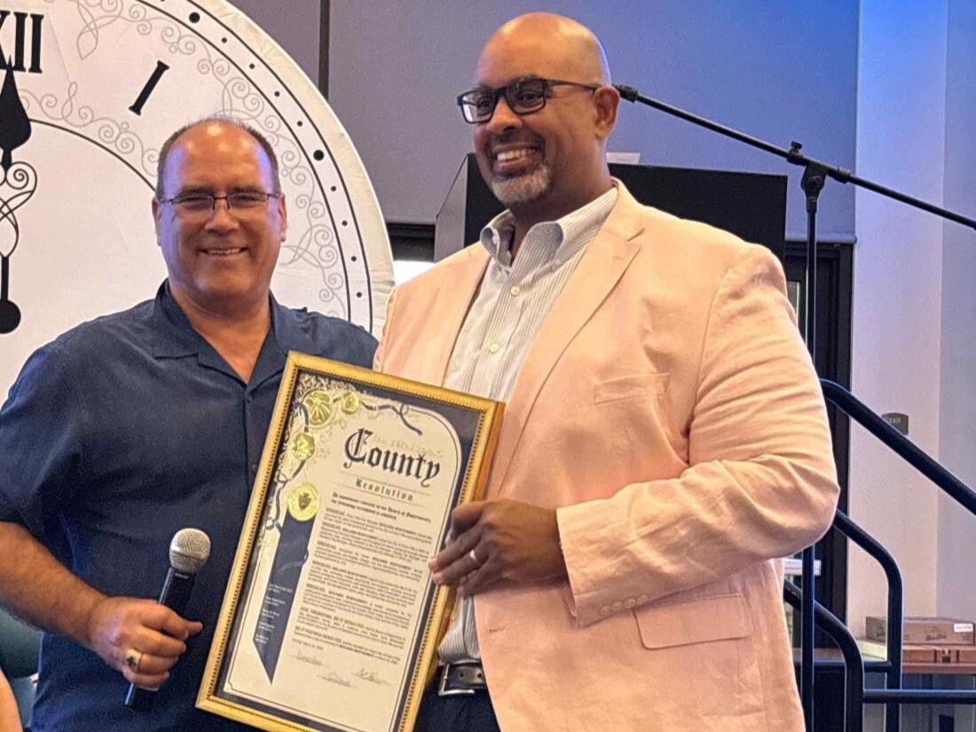 Supervisor Curt Hagman presents framed county certificate during community recognition event.