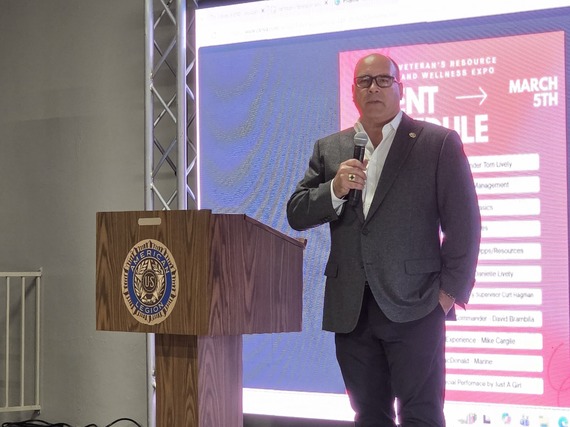 Supervisor Curt Hagman standing on stage, speaking into a microphone at the 2026 Veterans Resource and Wellness Expo.