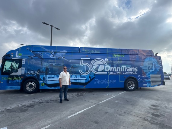 Supervisor Curt Hagman standing beside the Omnitrans 50th anniversary bus featuring local cities.