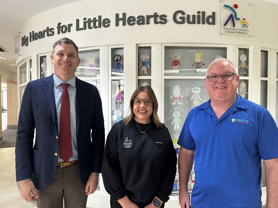 First 5 San Bernardino and Loma Linda University Children’s Hospital staff pose in front of an indoor display of colorfully decorated paper dolls.